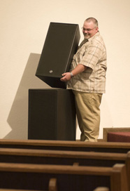 Man stacking speakers in a church setting