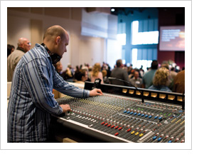 Worship tech director working at a large mixing console